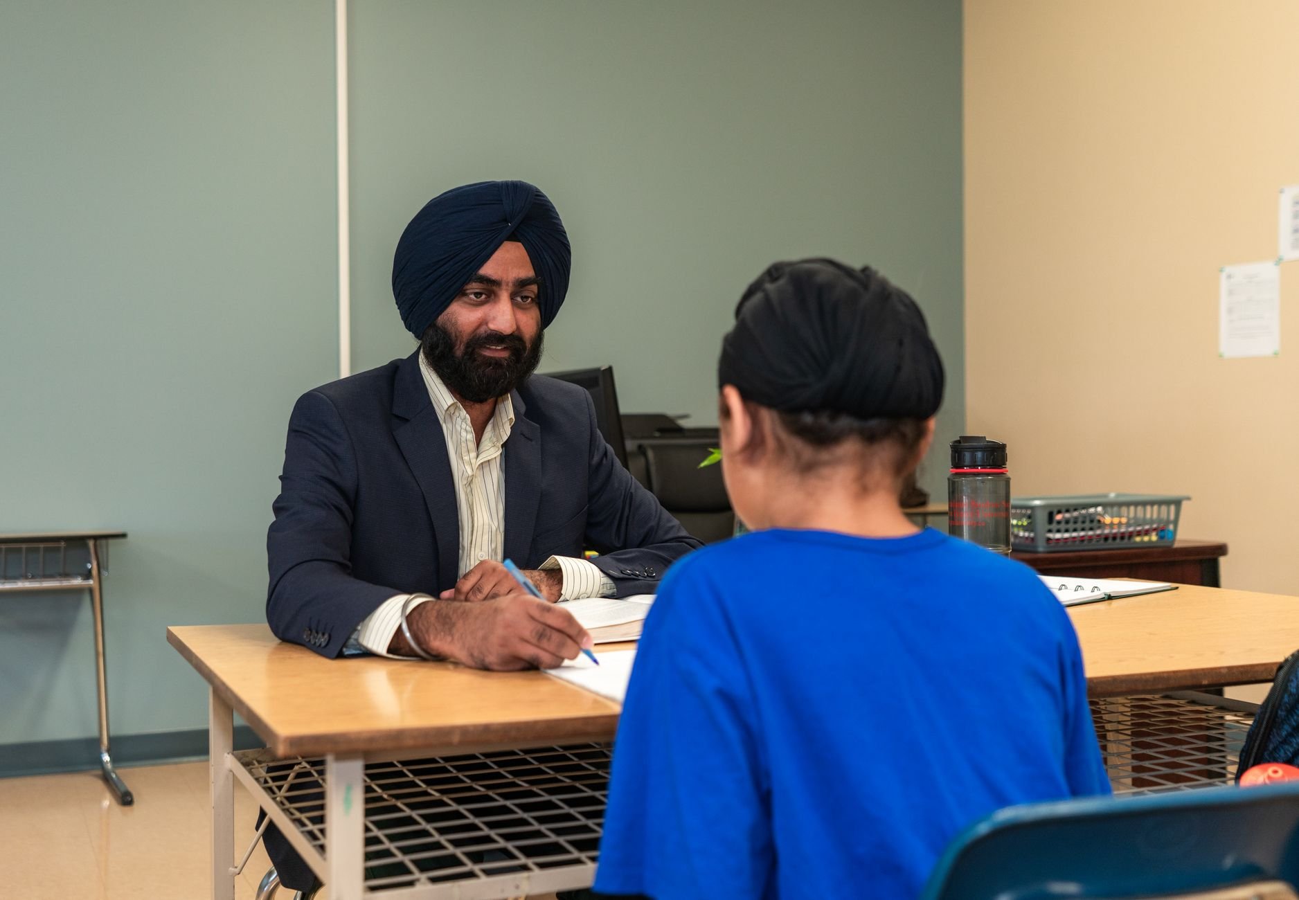A teacher and student engaging in a one-on-one discussion in a classroom setting